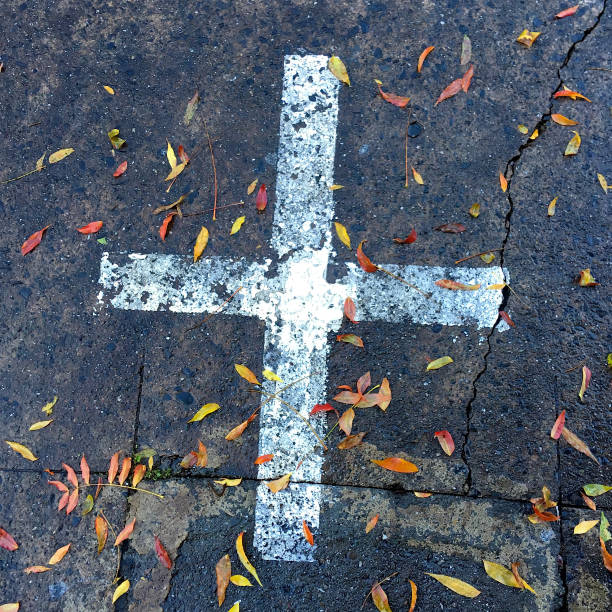 istock PAINTED CROSS AND LEAVES ON ROAD 1149324764