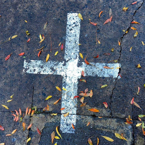 PAINTED CROSS AND LEAVES ON ROAD stock photo