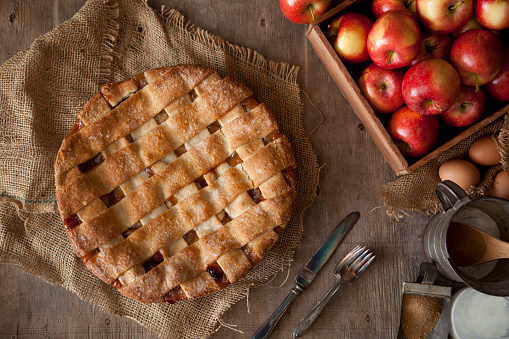 Fresh apple pie with ingredients on a wood background