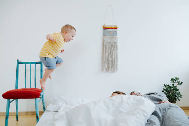 Cute little son trying to wake up his parents. stock photo