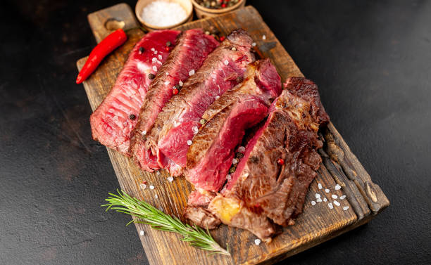 istock Grilled rib eye beef steak with herbs and spices on a stone background 1149337338