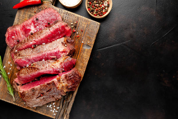istock Grilled rib eye beef steak with herbs and spices on a stone background 1149337361