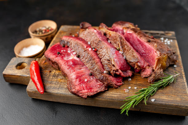 istock Grilled rib eye beef steak with herbs and spices on a stone background 1149337368