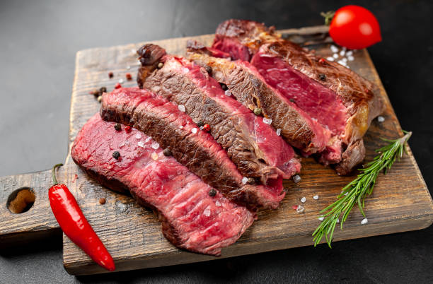 istock Grilled rib eye beef steak with herbs and spices on a stone background 1149337373