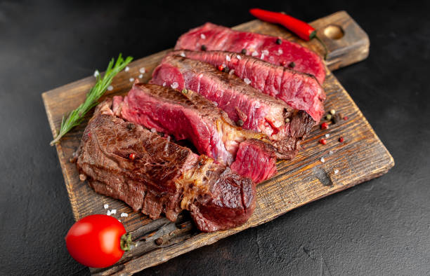 istock Grilled rib eye beef steak with herbs and spices on a stone background 1149337382