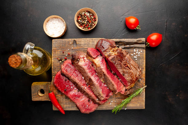 istock Grilled rib eye beef steak with herbs and spices on a stone background 1149337387