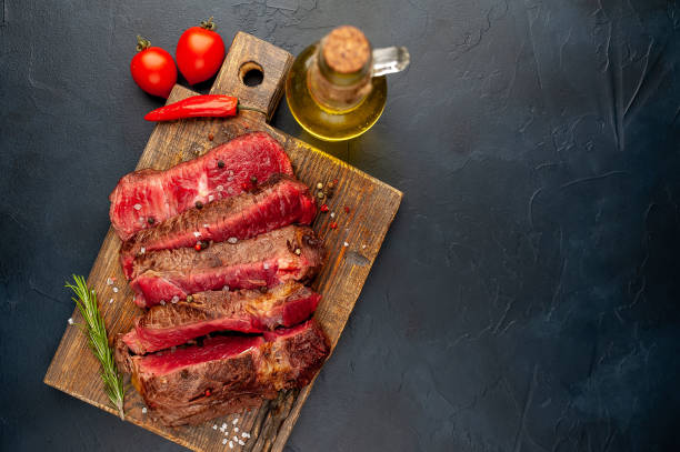 istock Grilled rib eye beef steak with herbs and spices on a stone background 1149337405