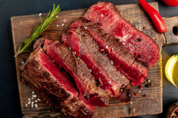 istock Grilled rib eye beef steak with herbs and spices on a stone background 1149337431
