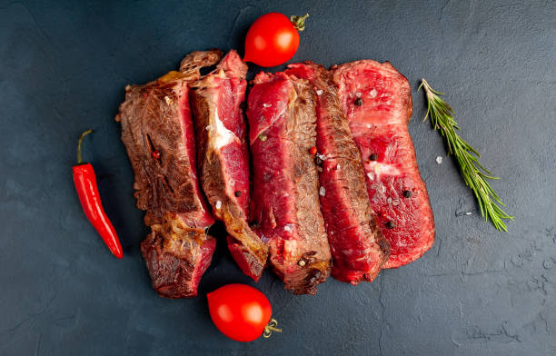 istock Grilled rib eye beef steak with herbs and spices on a stone background 1149337461