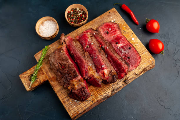 istock Grilled rib eye beef steak with herbs and spices on a stone background 1149337486