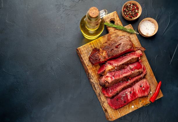istock Grilled rib eye beef steak with herbs and spices on a stone background 1149337559