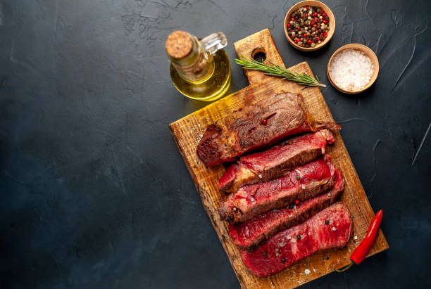 istock Grilled rib eye beef steak with herbs and spices on a stone background 1149337570