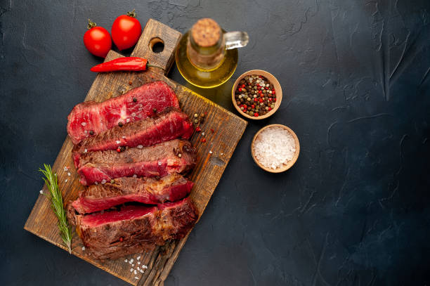istock Grilled rib eye beef steak with herbs and spices on a stone background 1149337695