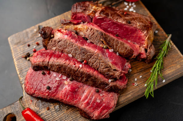 istock Grilled rib eye beef steak with herbs and spices on a stone background 1149337754