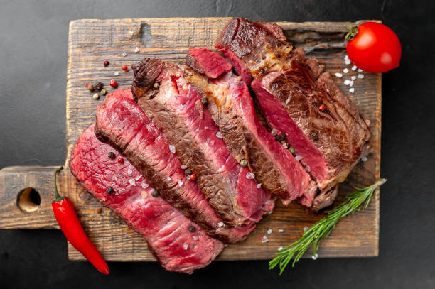 istock Grilled rib eye beef steak with herbs and spices on a stone background 1149337769