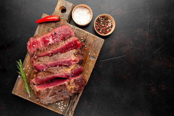 istock Grilled rib eye beef steak with herbs and spices on a stone background 1149337815