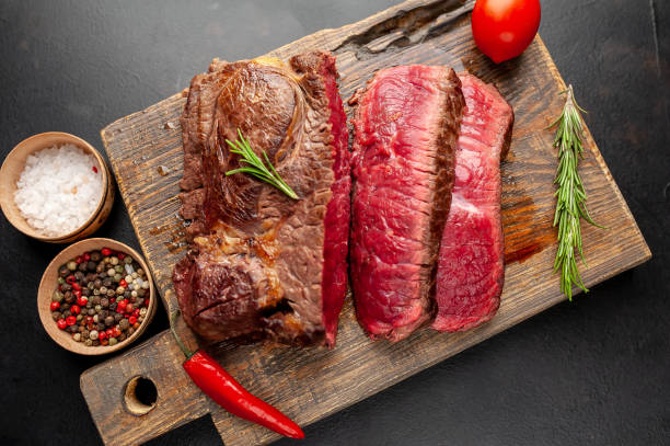 istock Grilled rib eye beef steak with herbs and spices on a stone background 1149337850
