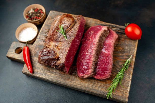 istock Grilled rib eye beef steak with herbs and spices on a stone background 1149337886