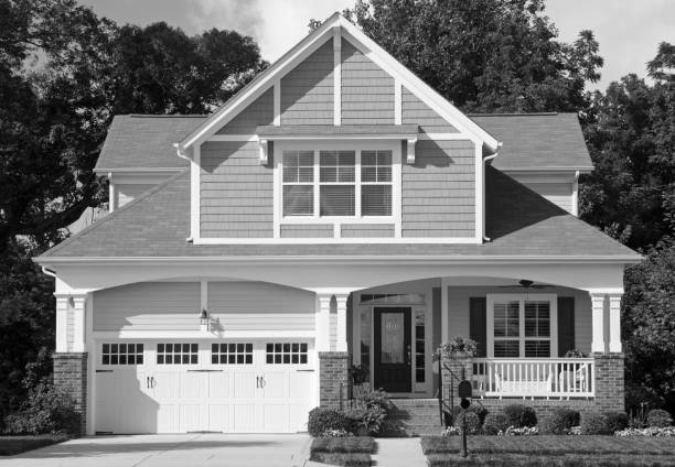 Traditional Victorian, Cottage Style Homes in a Residential Neighborhood captured in black and white McAdenville, North Carolina, USA - July 6, 2013: The American Dream is pictured in this iconic image of a row of new, Victorian-style homes in the McAdenville neighborhood development. Most American homes are now built on smaller lots with sidewalks and tree-lined streets in the suburbs of large cities. Traditional architectural styles blend with modern amenities, fixtures and details. monochrome house stock pictures, royalty-free photos & images