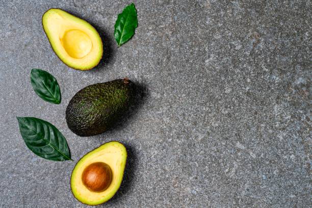 istock Opened avocado showing seed on textured stone background. top view 1149346232