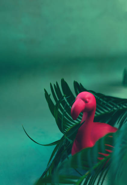istock Pink flamingo toy between palm tree leaves. Minimal summer concept 1149348750