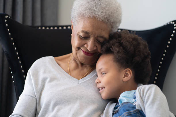 Beautiful ethnic Grandma is laughing with her young Granddaughter. A young and attractive grandmother of African descent is spending time with her granddaughter. They are laughing. granddaughter stock pictures, royalty-free photos & images
