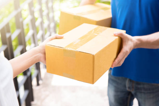 istock Delivery man in blue uniform handing parcel box to recipient 1149369389