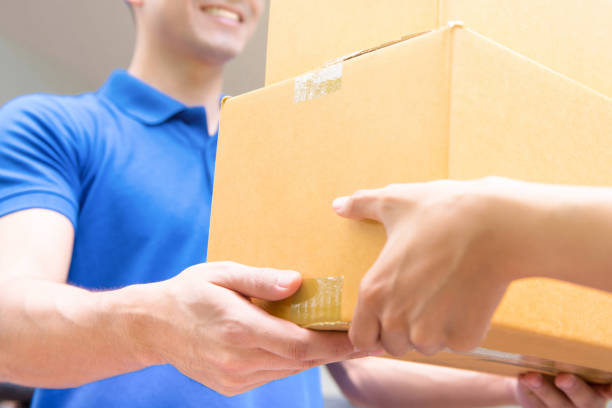 istock Delivery man in blue uniform handing parcel boxes to recipient 1149369398