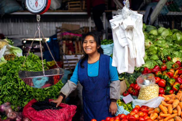 Cusco, Peru - March 31 2019: Indigenous young woman smiling and selling vegetables at \