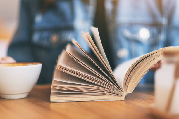 istock a woman holding and reading a vintage novel book 1149388478