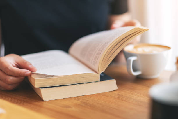 istock a woman holding and reading a vintage novel book 1149388498