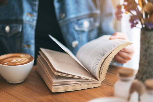 istock a woman holding and reading a vintage novel book 1149388517