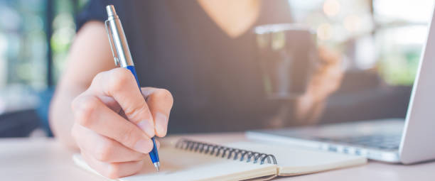 istock Woman hand is writing on a notepad with a pen in office.Web banner. 1149394339