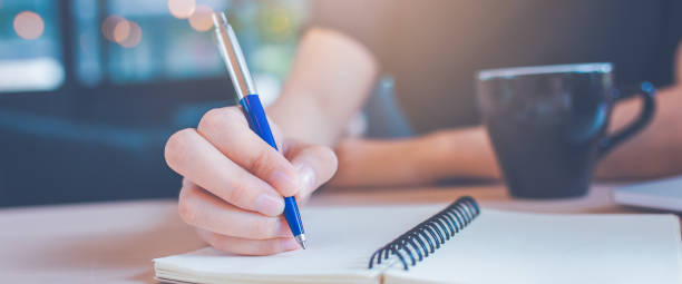 istock Woman hand is writing on a notepad with a pen in office.Web banner. 1149394340