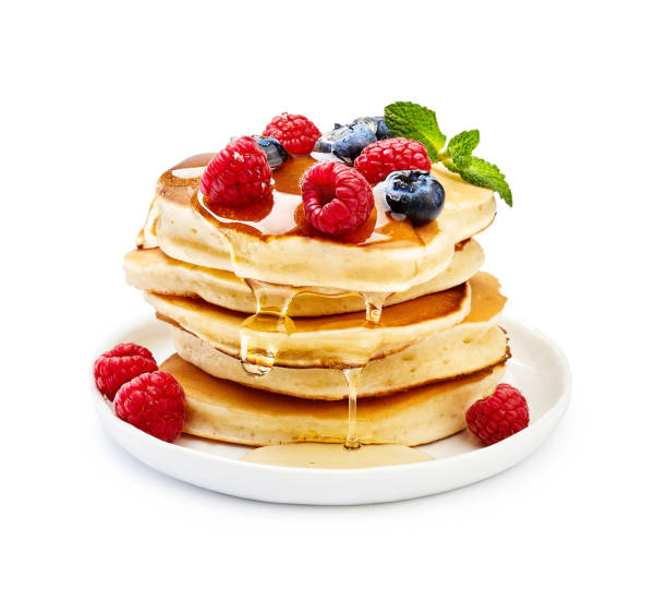 Delicious pancakes with berries, honey or maple syrup. Homemade pancakes and sweet syrup on white plate isolated. stock photo