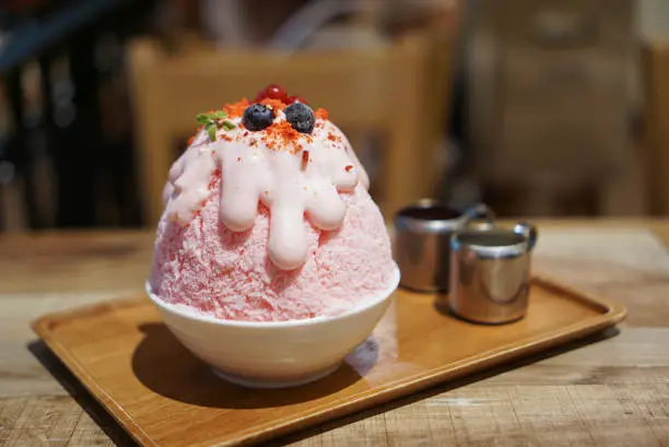 Japanese sweet dessert in Thai Style, pink milk shaved ice topped with pink whipped cream and berry fruit.