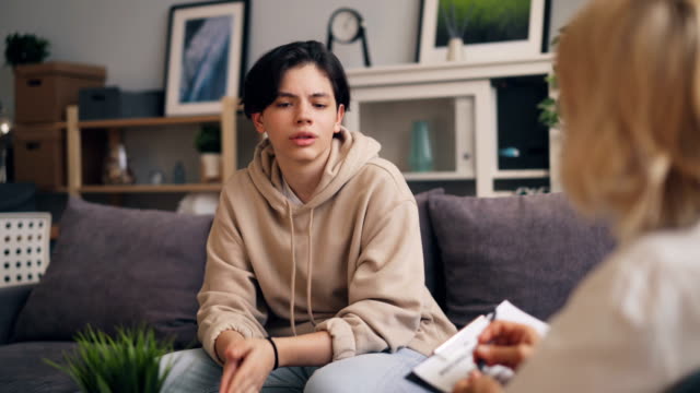 Nervous teenager communicating with female psychoanalyst during session
