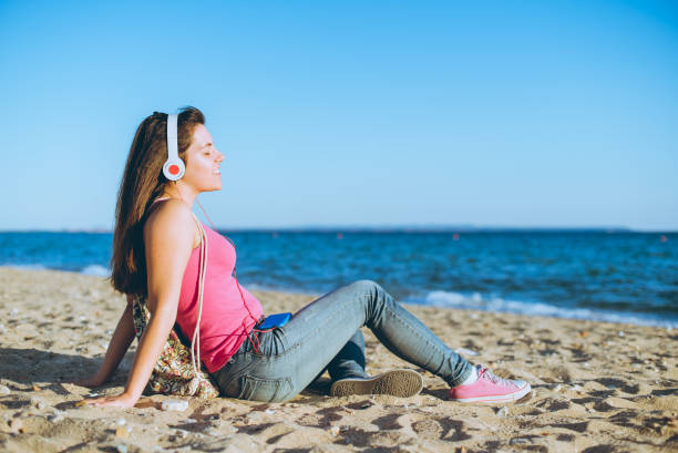 istock Woman enjoying music on the beach 1149405864