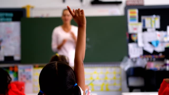 Rear view of schoolgirl raising hand in the classroom 4k