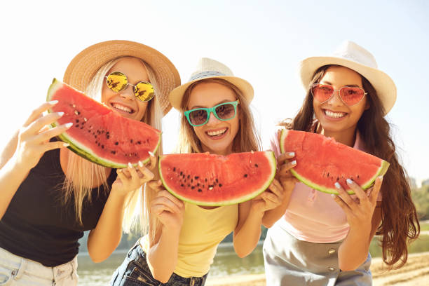 istock Girlfriends at a party eating a watermelon on the beach. 1149410913