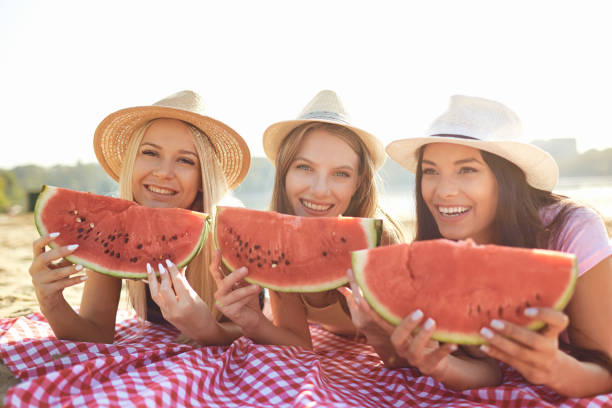 istock Girlfriends at a party eating a watermelon on the beach. 1149410917