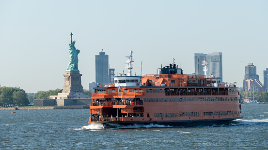 An image of a ferry at downtown New York City with Statue of Liberty