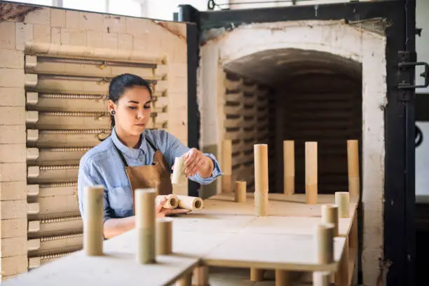 Woman prepare kiln in pottery factory.