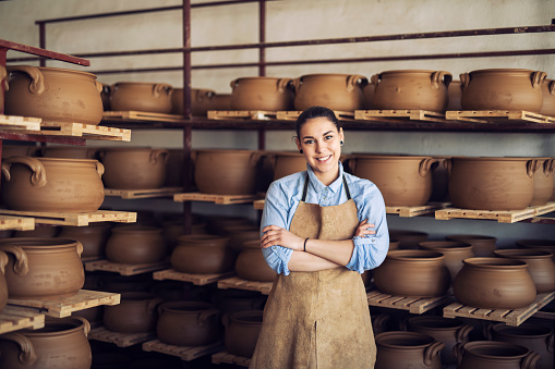 Portrait of a smiling young woman in a ceramic studio.