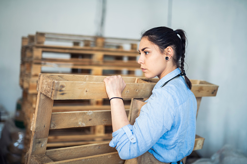 Woman working and holding wooden pallet.