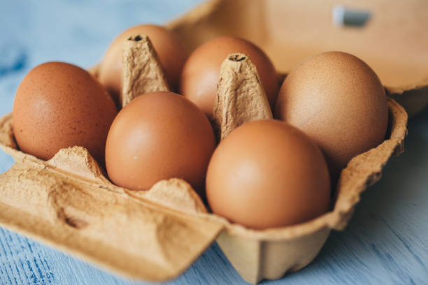яйца фон. вид крупным планом яиц в коробке на деревянном столе. - яйцо животного стоковые фото и изображения