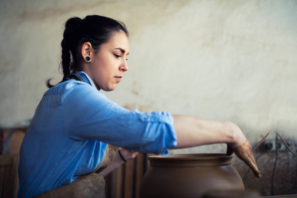 Woman working on pottery wheel.