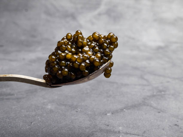 istock Metal spoon with black caviar on grey background 1149428168