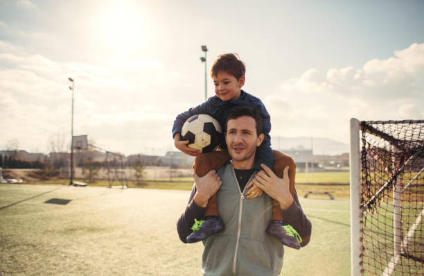 vater und sohn auf einem fußballplatz - sports event goal soccer net stock-fotos und bilder