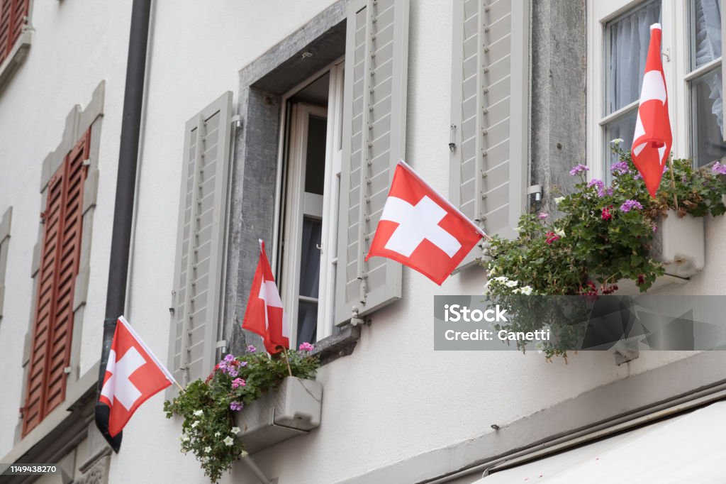 swiss flags swiss flags on the window of a old apartment house in Chur National Holiday Stock Photo